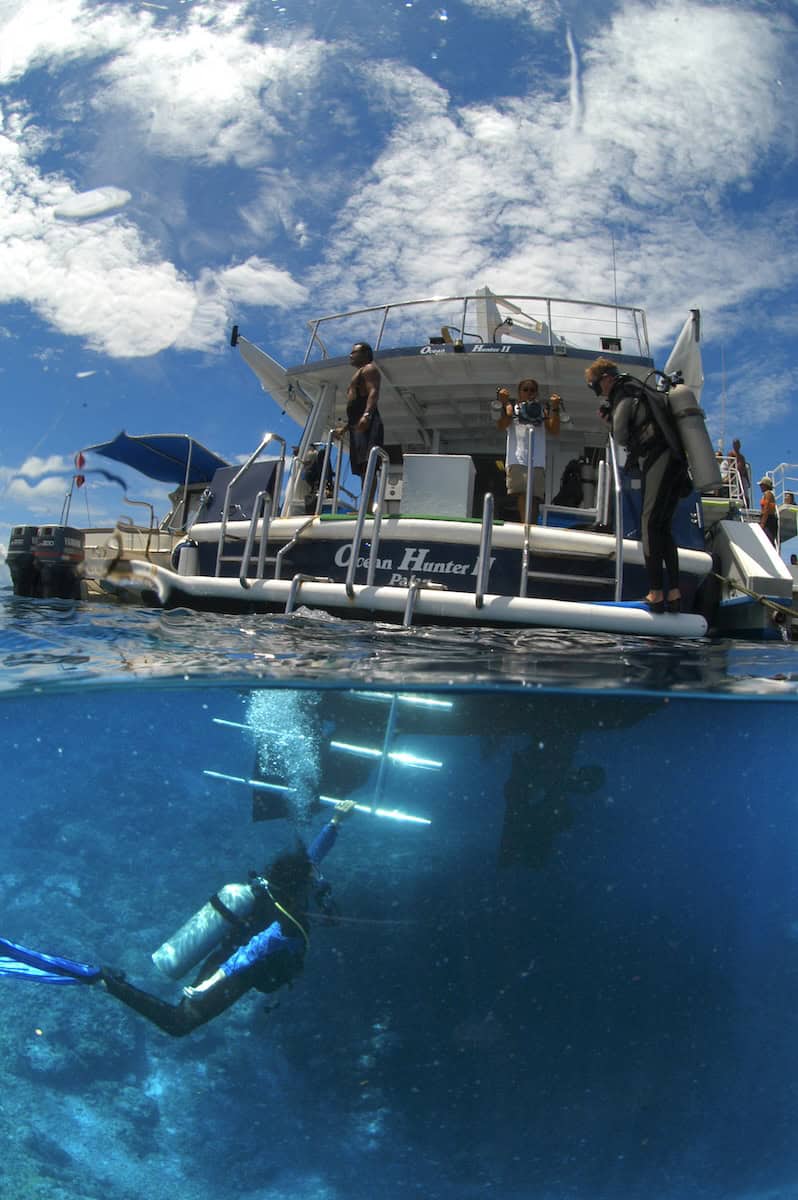 Scuba divers entering water off stern of Ocean Hunter II dive boat