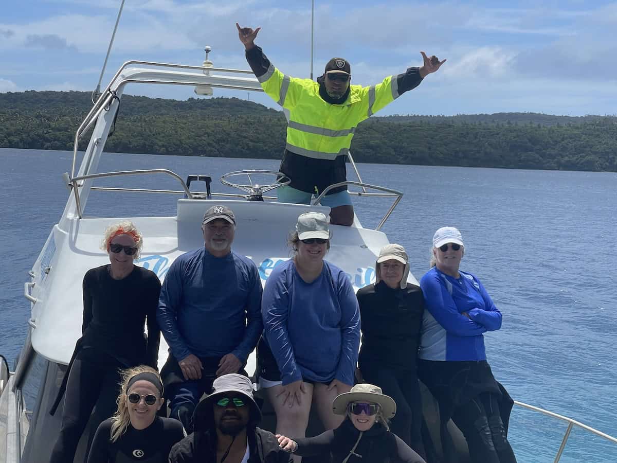Travelers post at boat bow for group photo in Tonga